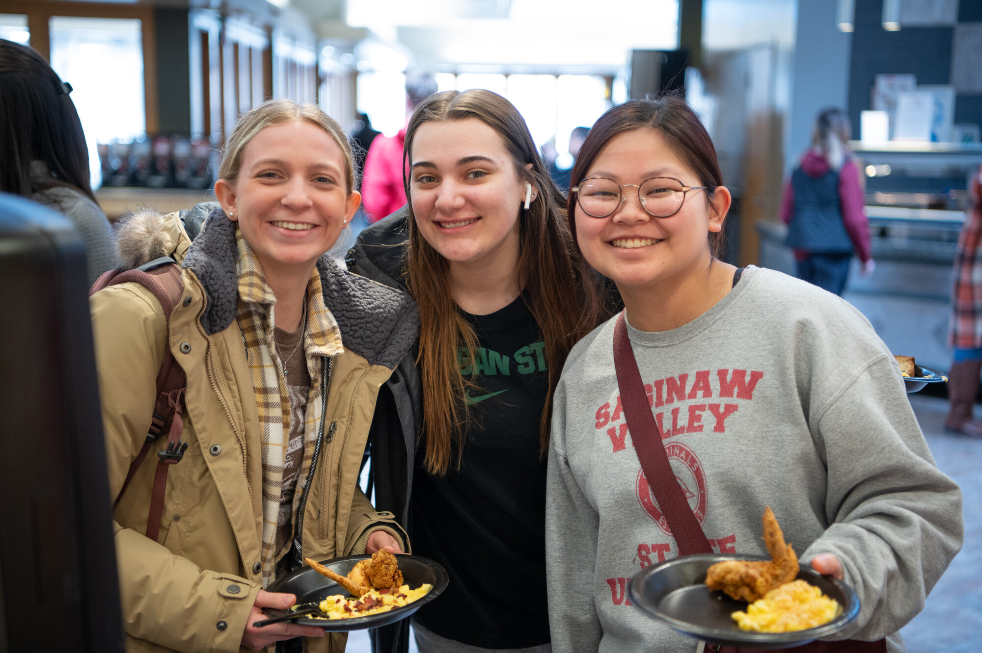 Three students posing for photo, holding food